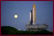 STS-86 Atlantis on crawler transport rolling out to the launch pad; full moon rises behind the shuttle